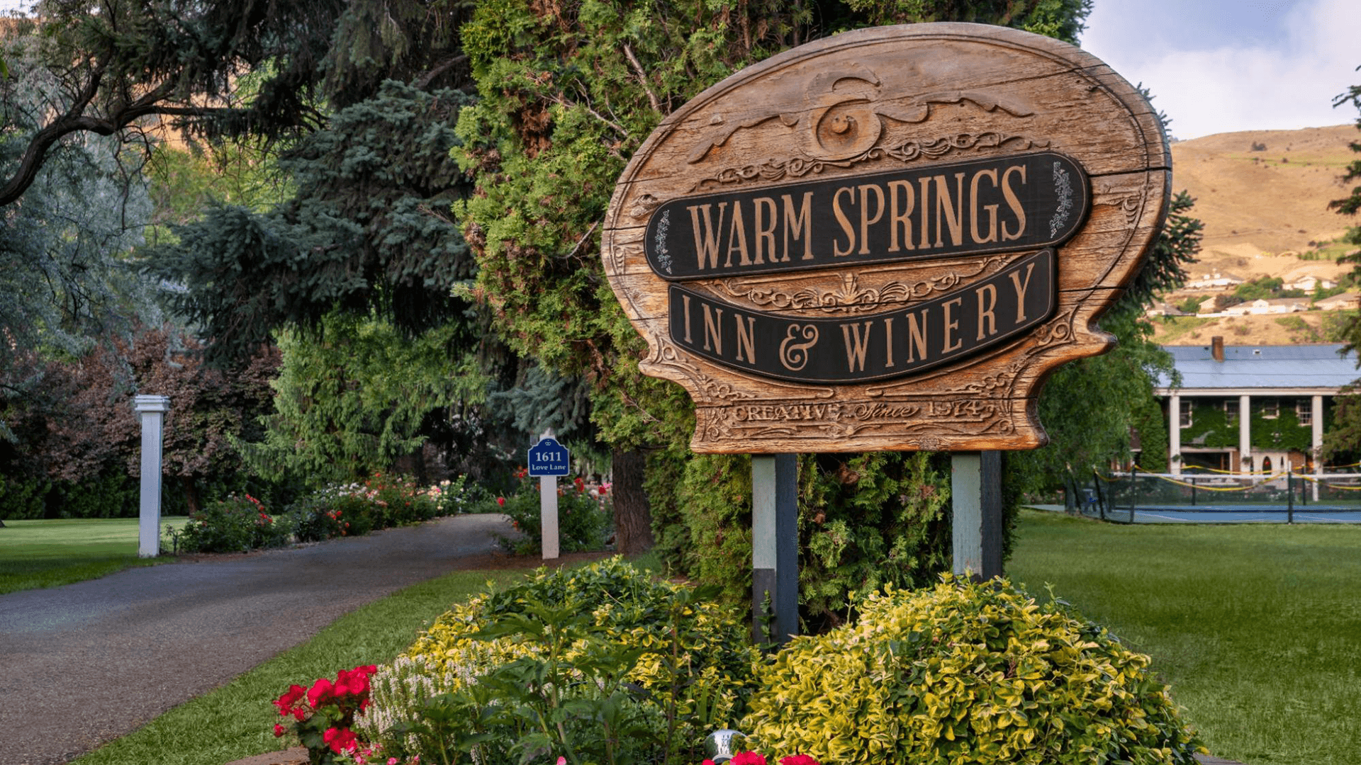 Sign for Warm Springs Inn & Winery surrounded by greenery and flowers.