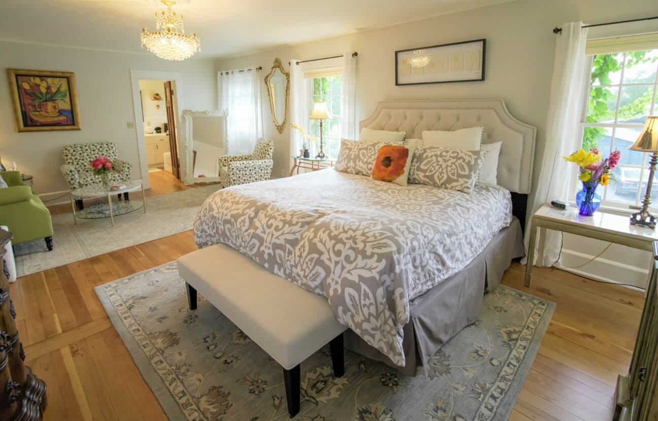 A cozy, well-decorated bedroom featuring a stylish bed, floral armchairs, and a warm ambiance.