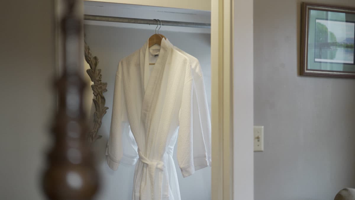 A white bathrobe hangs in a closet.
